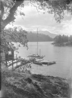 Untitled (sailboat and rowboats docked by cabin)