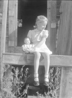 Untitled (little girl sitting on doorstep with a doll)