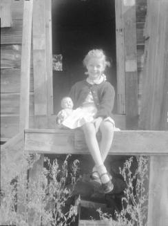 Untitled (little girl sitting on doorstep with a doll)
