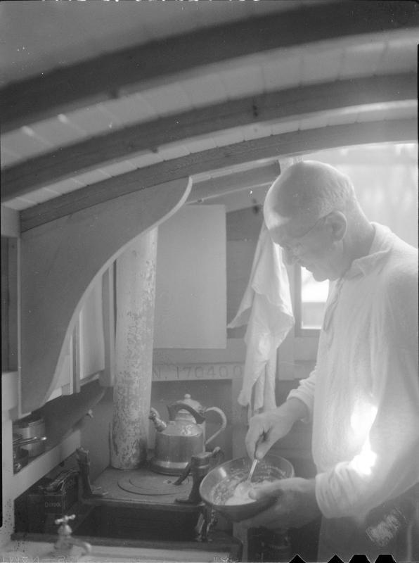 Untitled (man cooking in cabin of boat)