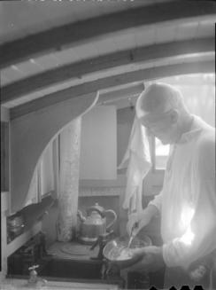 Untitled (man cooking in cabin of boat)