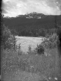 Untitled (figure sitting by lake and mountains)