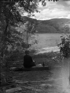 Untitled (figure sitting by lake)