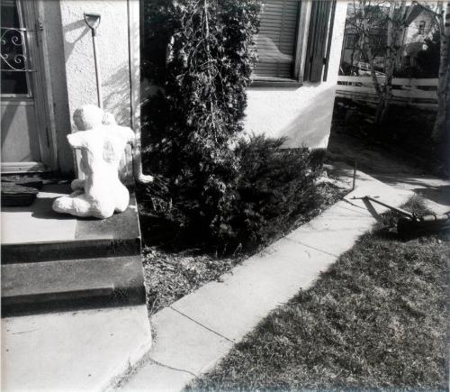 Statue and Shovel by a House