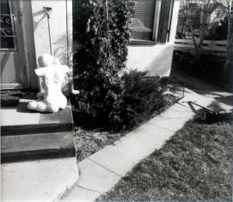 Statue and Shovel by a House