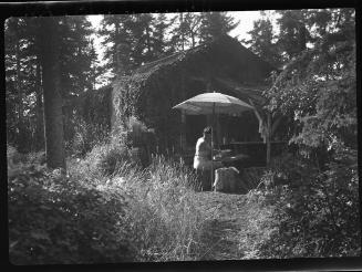 Untitled (woman sitting under umbrella at cabin)
