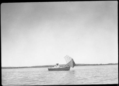 Untitled (man in boat with sun umbrella)