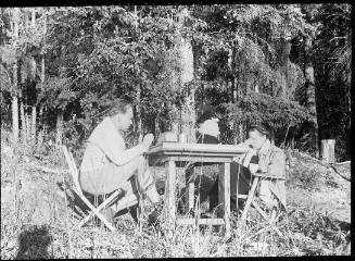Untitled (couple sitting at table in woods)