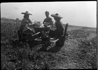 Untitled (group sitting at table by lake)